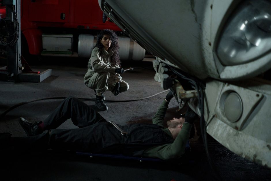 Two mechanics performing maintenance on a truck inside a garage setting.